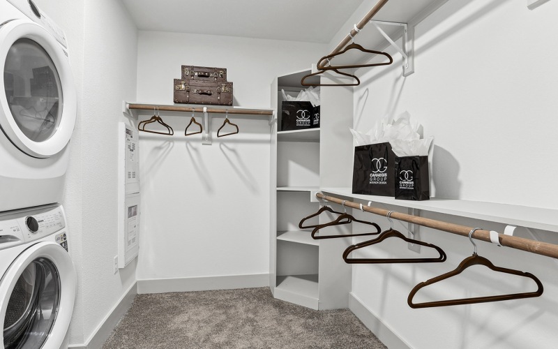 a walk-in closet with a washer and dryer